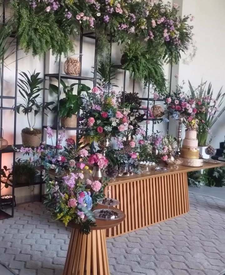 Estrutura coberta de flores e folhagens sobre a mesa do bolo em festa de 15 anos