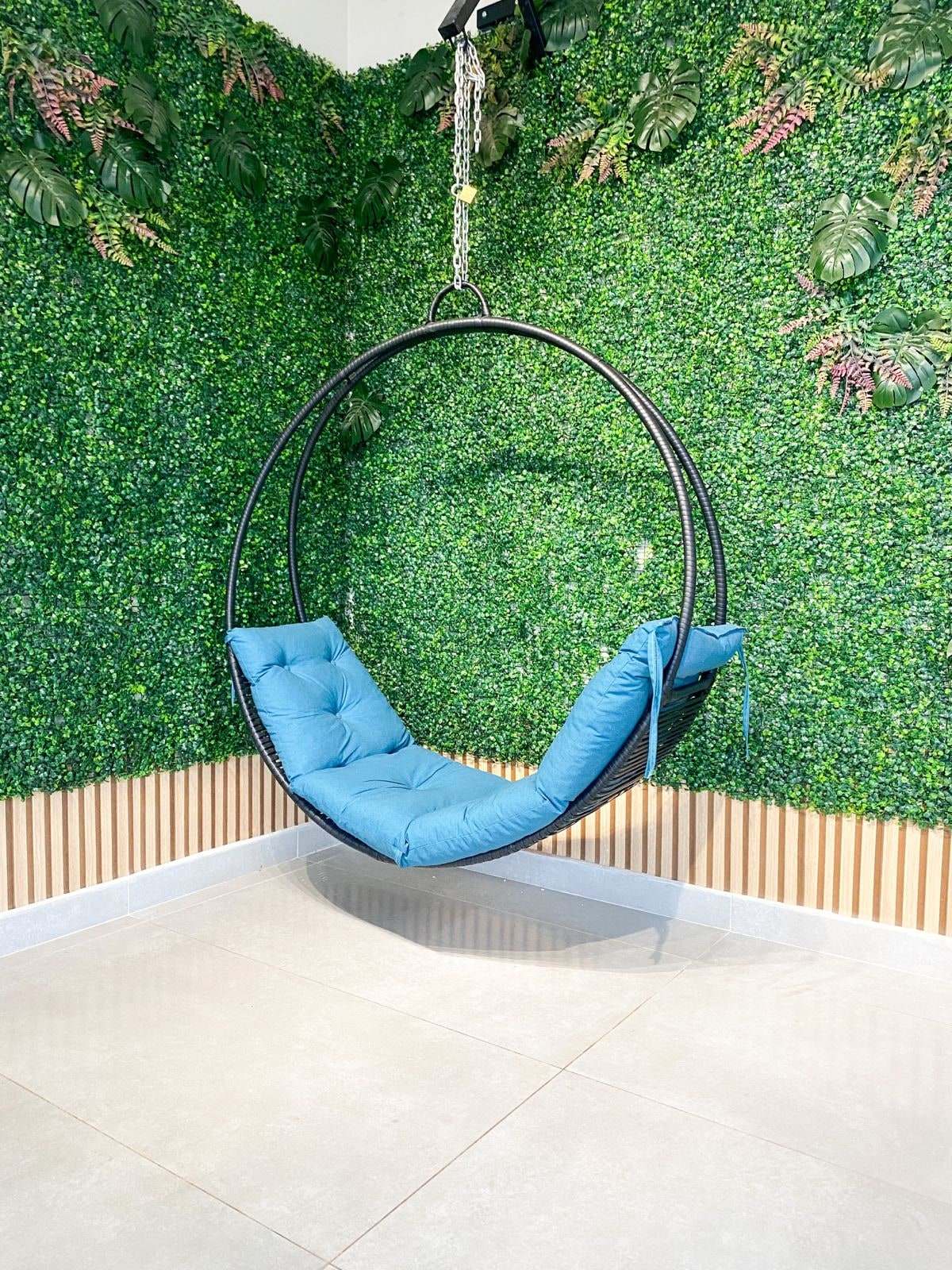 Área de fotos com jardim vertical e balanço suspenso de assento azul