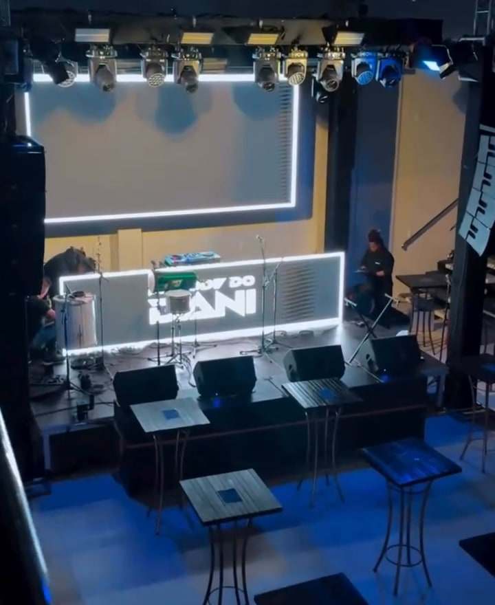Palco montado com painel de LED e bistrôs no salão, antes do show