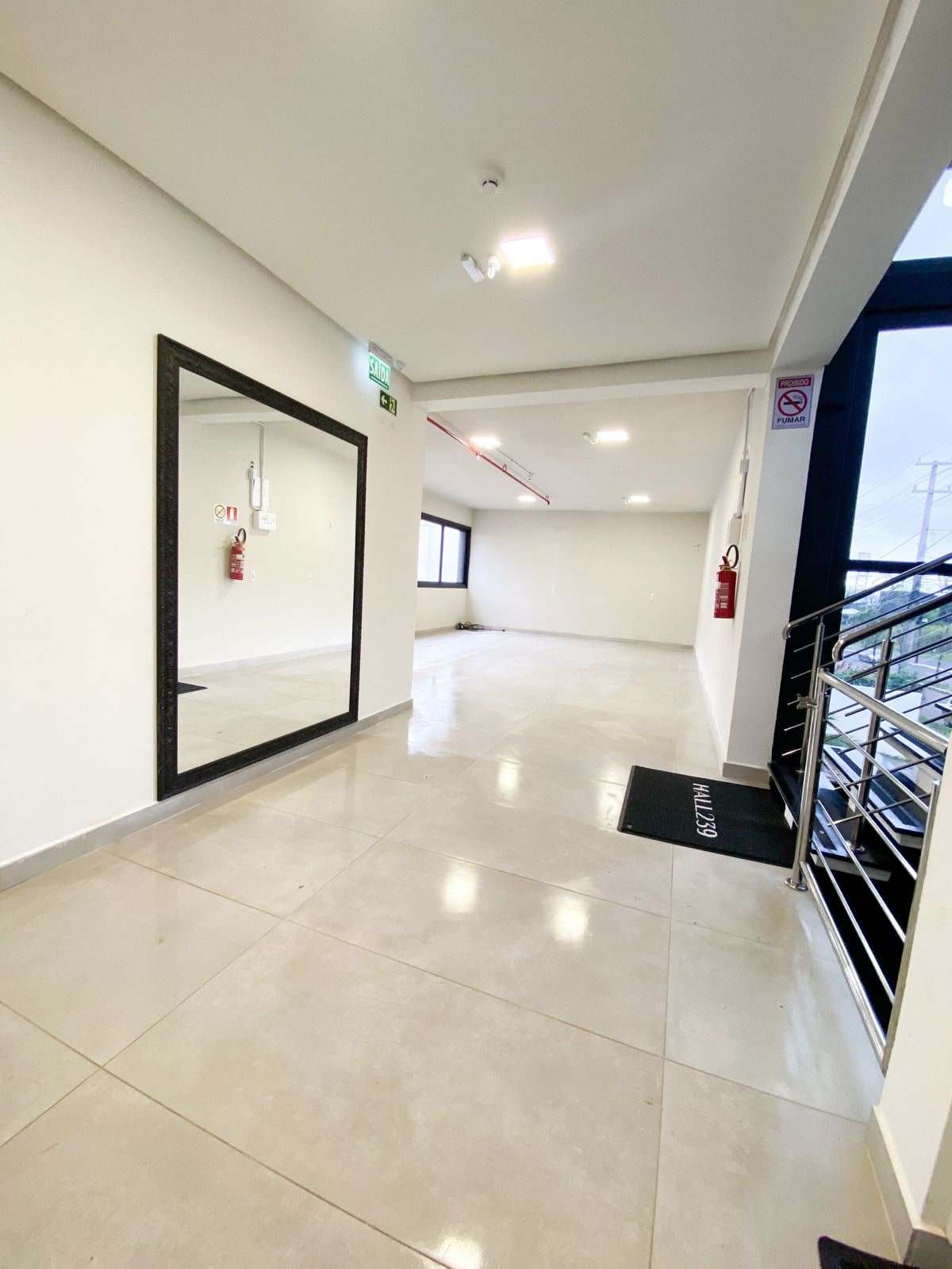 Hall de recepção com espelho de moldura preta e acesso ao salão